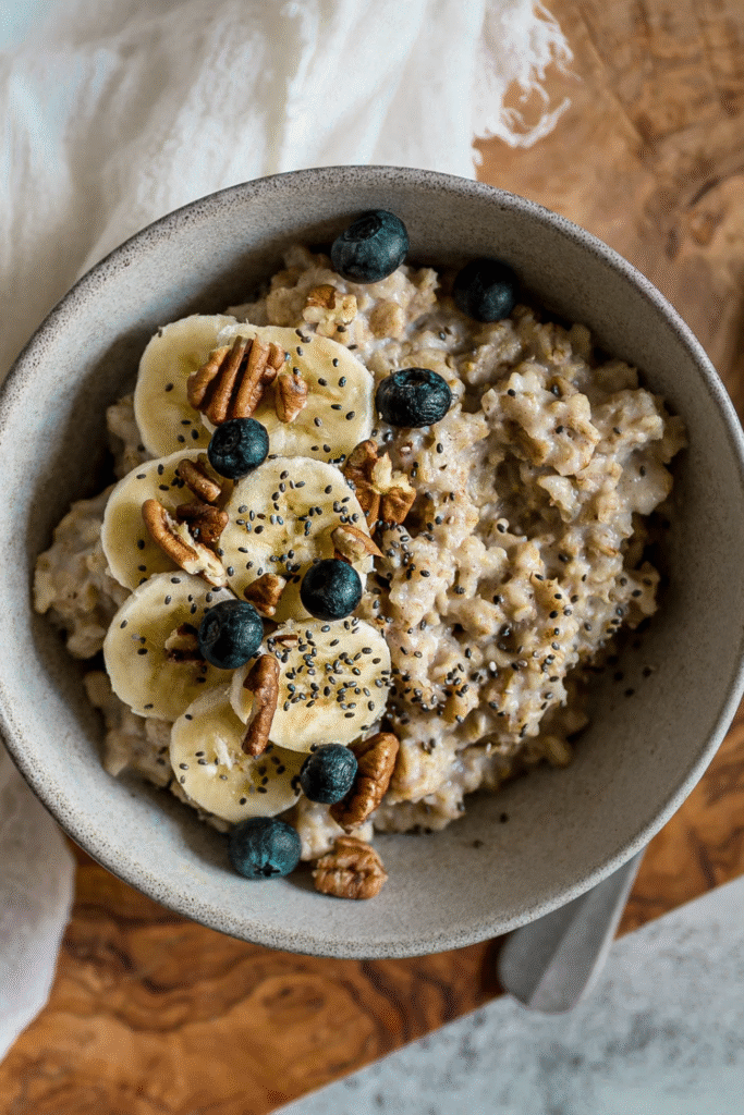 a bowl of oatmeal with chia seeds, blueberries, and walnuts in it on top of a wooden table with a white linen table cloth to the side with free recipe cards