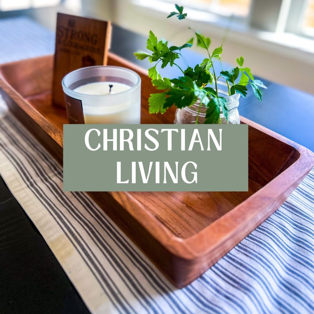 christian living banner over a centerpiece on a black table; wooden centerpiece with a candle, herbs, and art work in it on top of a striped runner