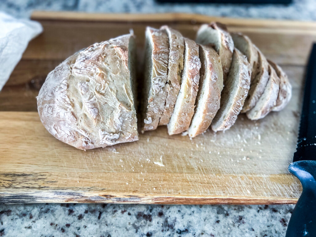 homemade bread on a wooden cutting board on top of a granite countertop