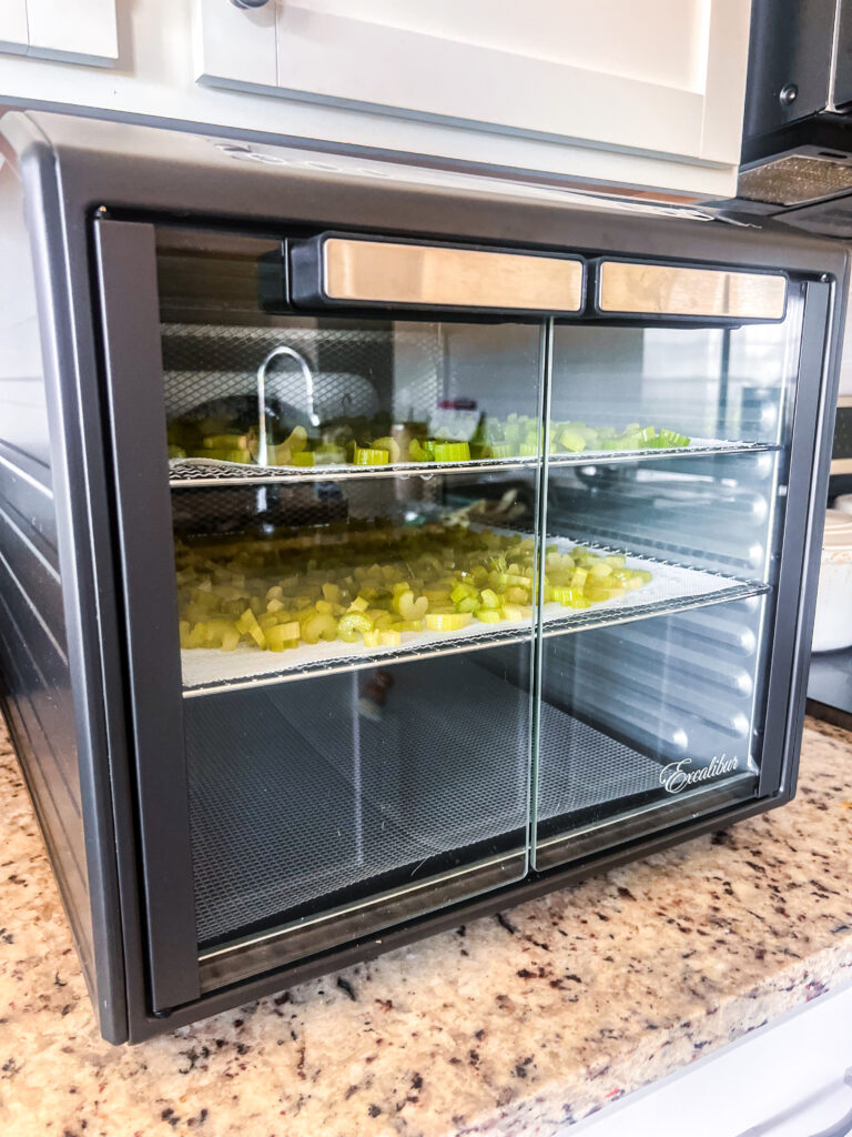 food dehydrator closed and on with two trays of cut celery inside