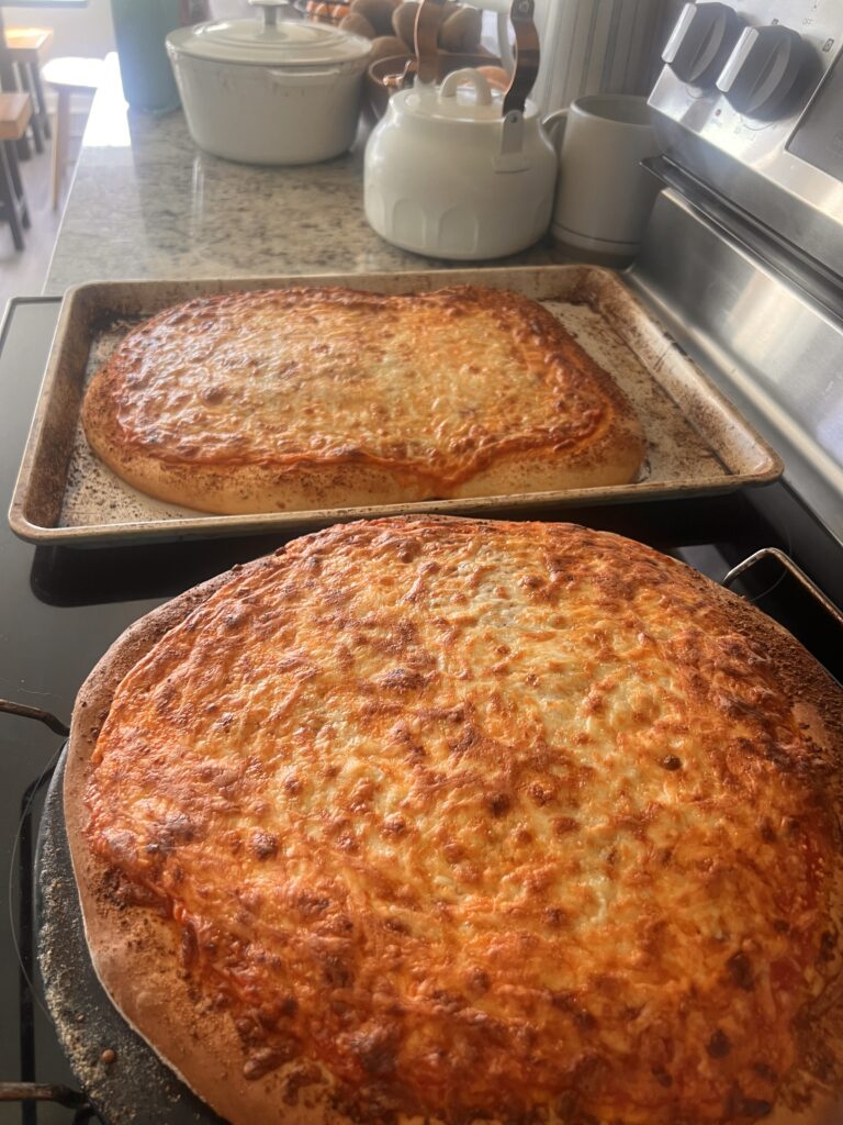 two cooked homemade pizzas on top of a stove